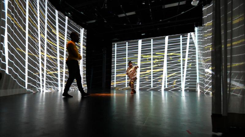 a wall of light strings with silhuettes of people moving through the space