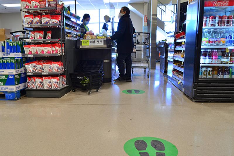 Customer wearing mask and social distancing in check-out line of grocery story