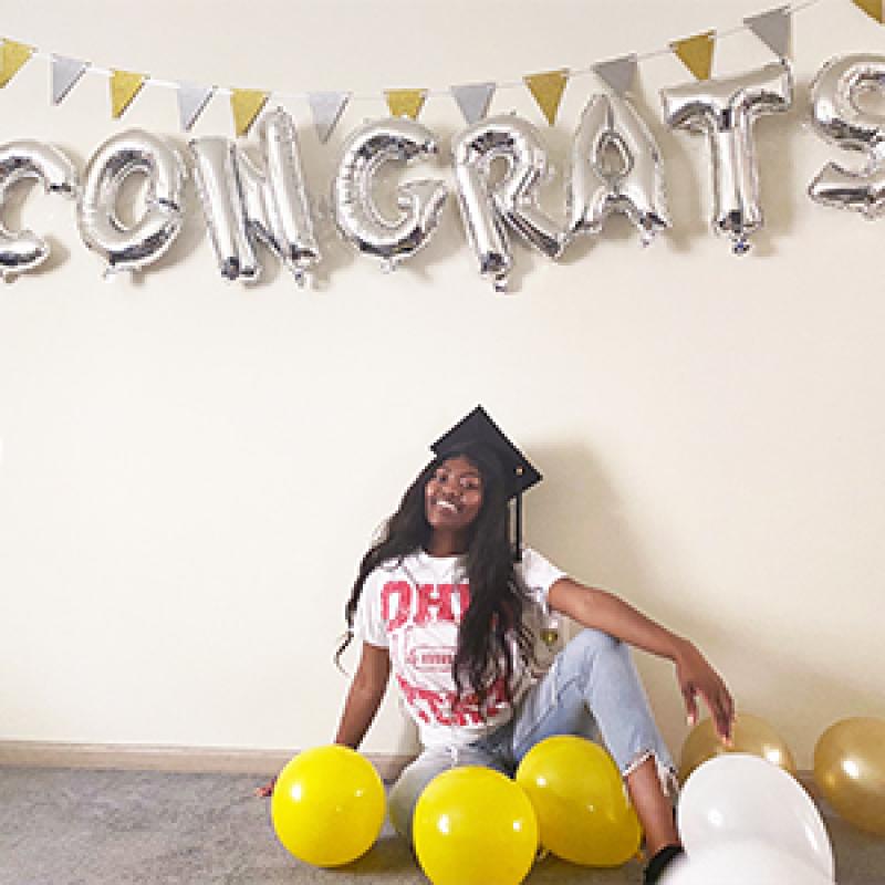 Dube poses under "Congrats" balloons
