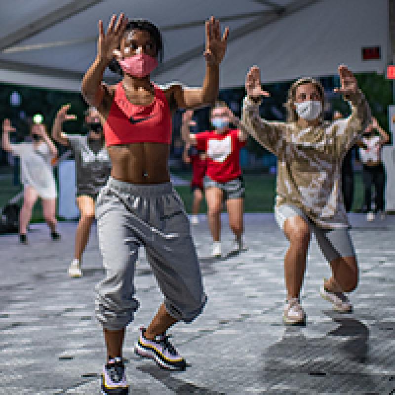 Students dance during a hip hop dance class in a specialized outdoor tent on the South Oval. 