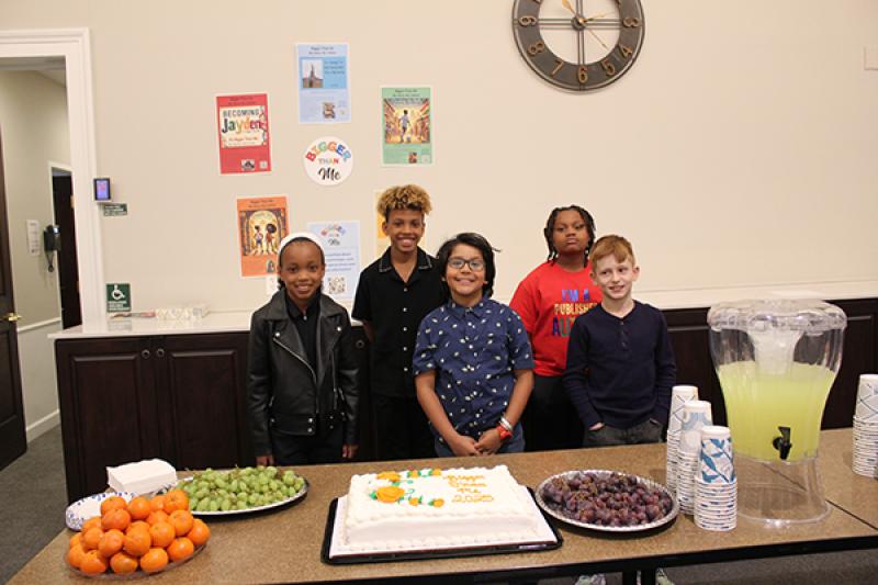All five children at the showcase pose with a cake celebrating their efforts