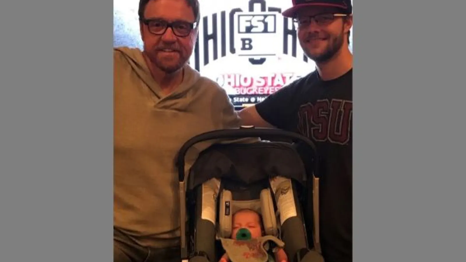two men and a baby watching a football game