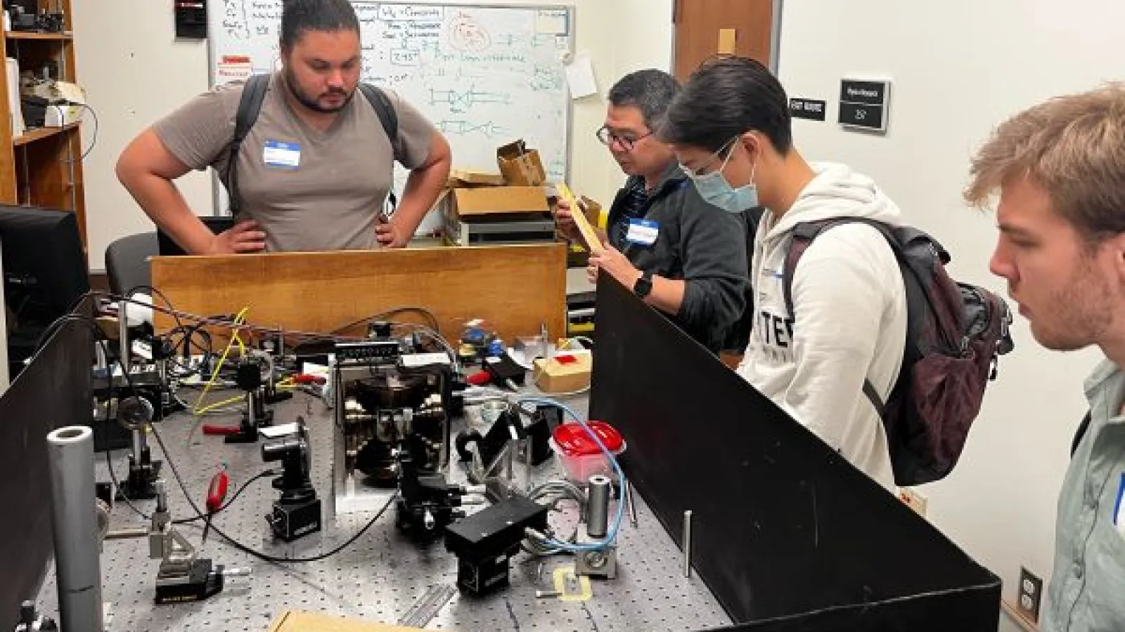 students and faculty look at a physics experiment
