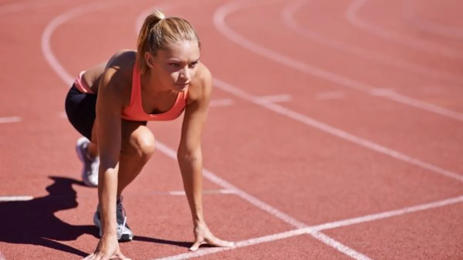 a young female runner at the starting line of a race, looking determined