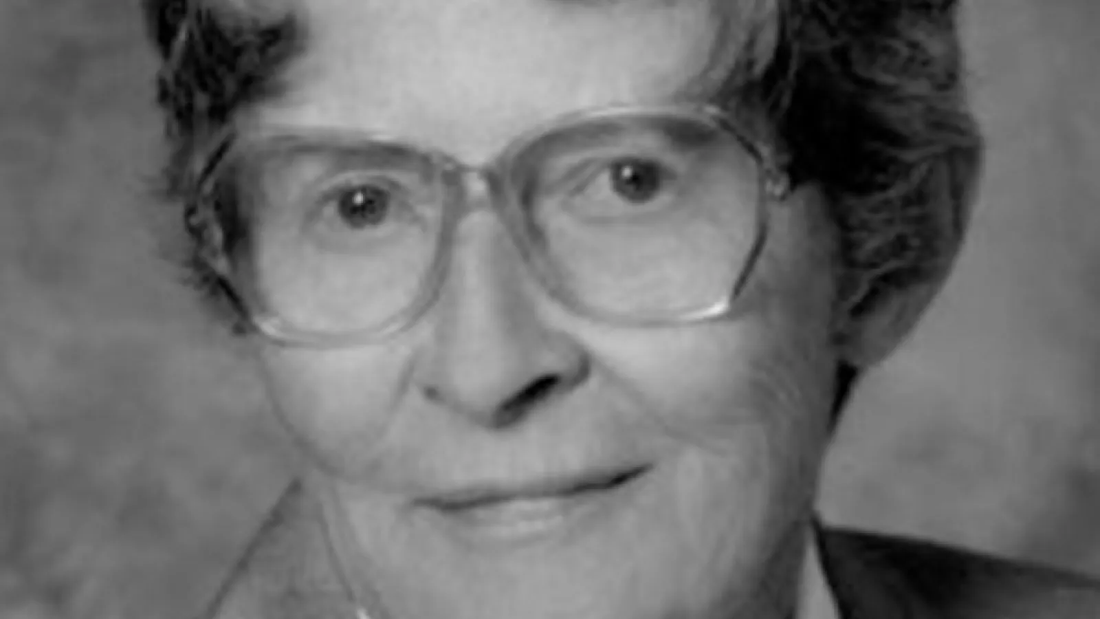 A closeup of Joan Huber, a woman wearing glasses.