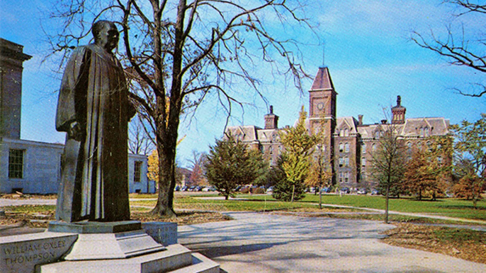 A postcard of the Thompson statue with University Hal behind it. 
