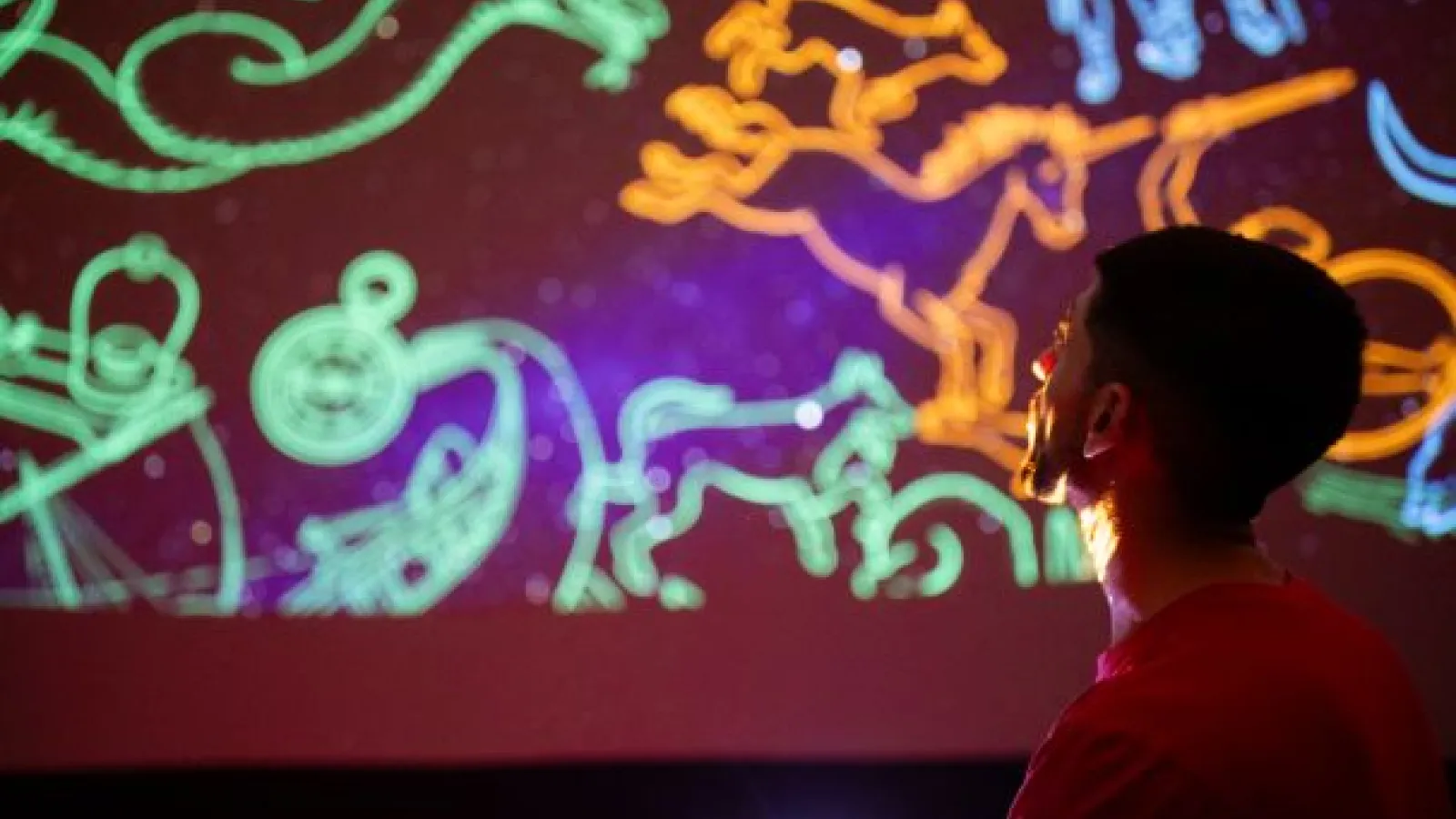 A student in front of astrology symbols projected onto the ceiling.