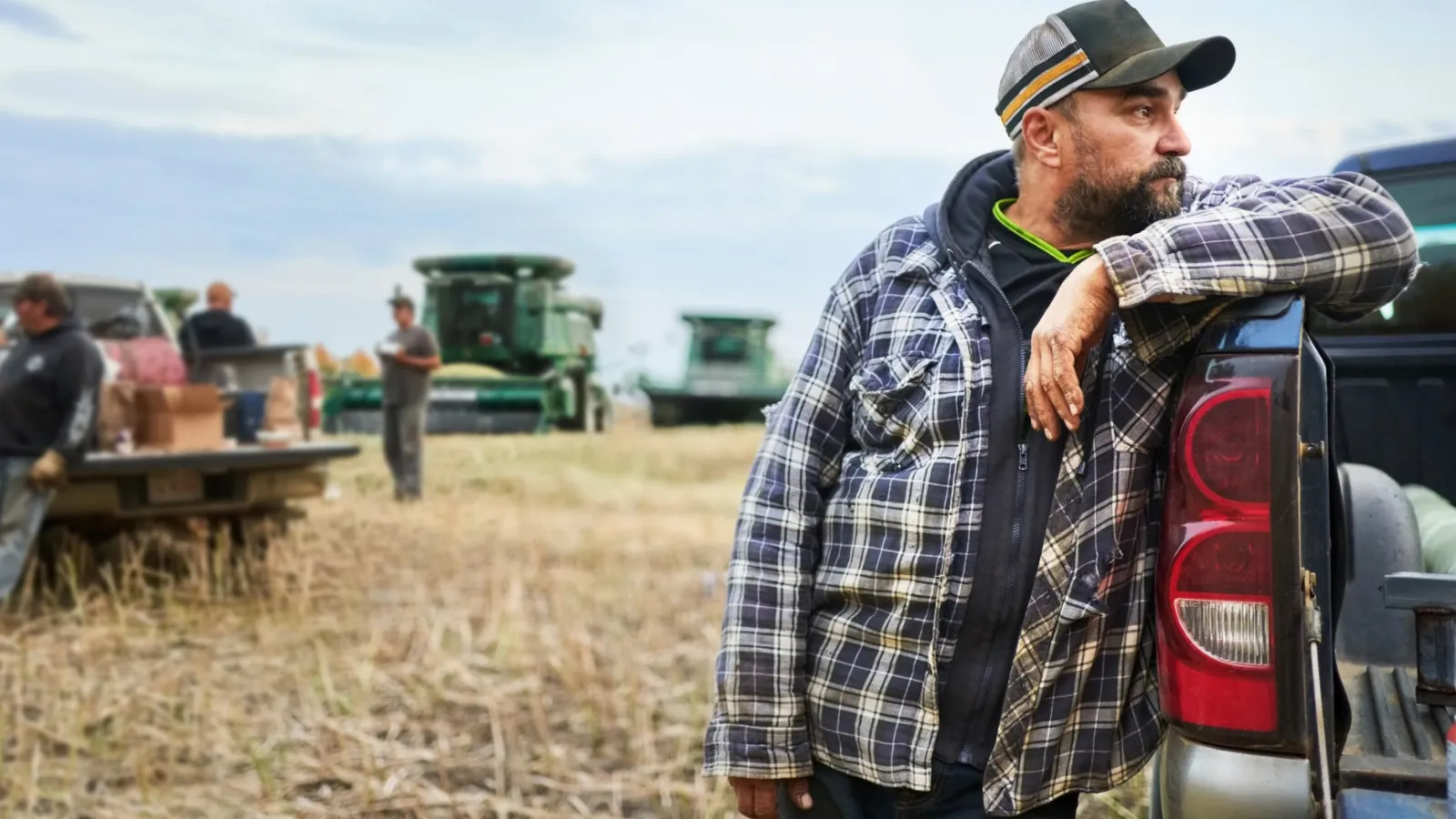 A man standing by a pickup truck in a field