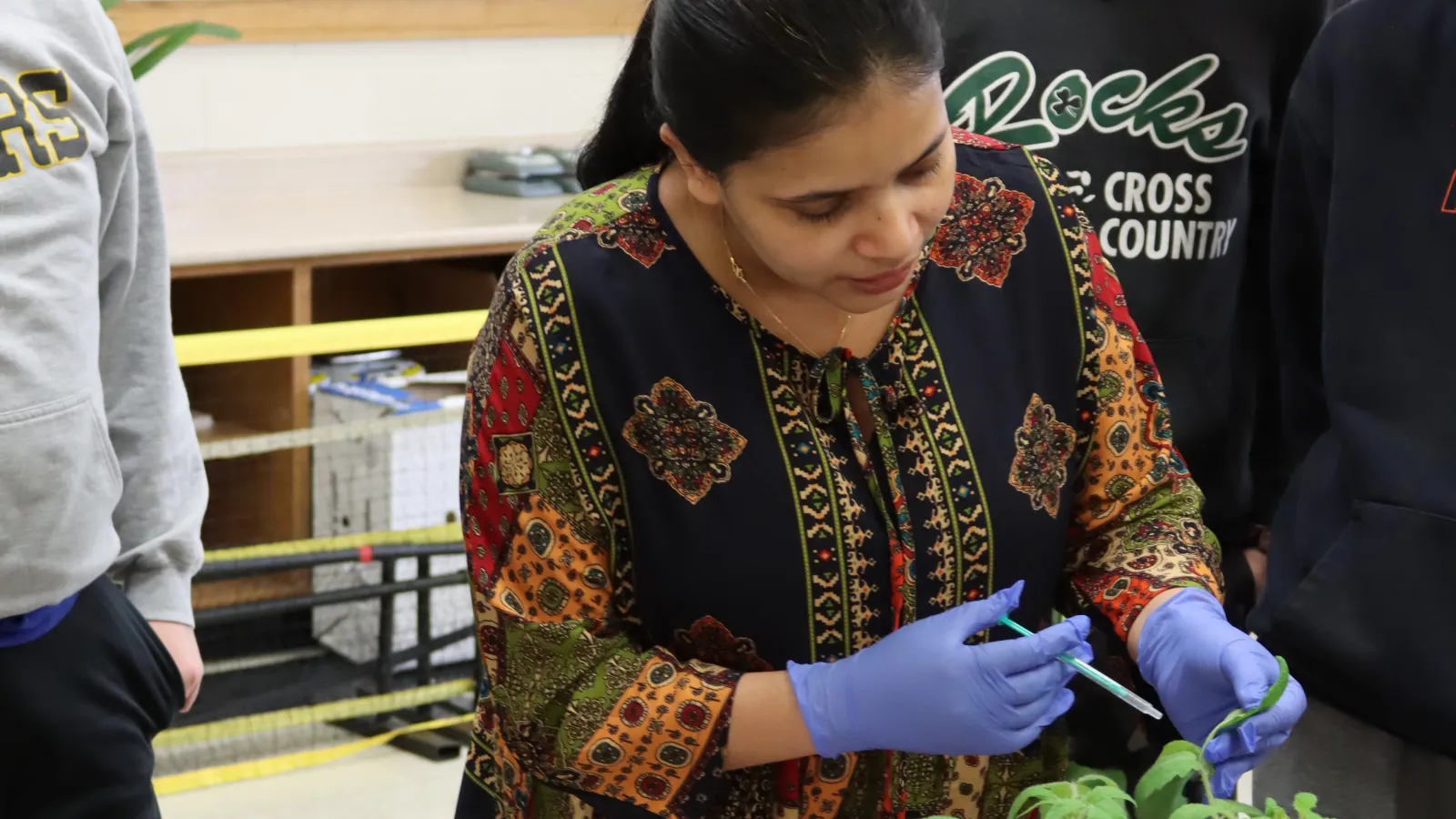 Patel showing students one method of adding plant protection to sample plants