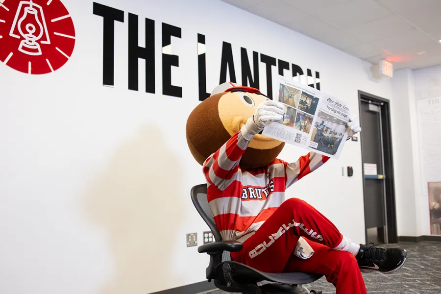 Brutus Buckeye sits in The Lantern newsroom reading a copy of the paper