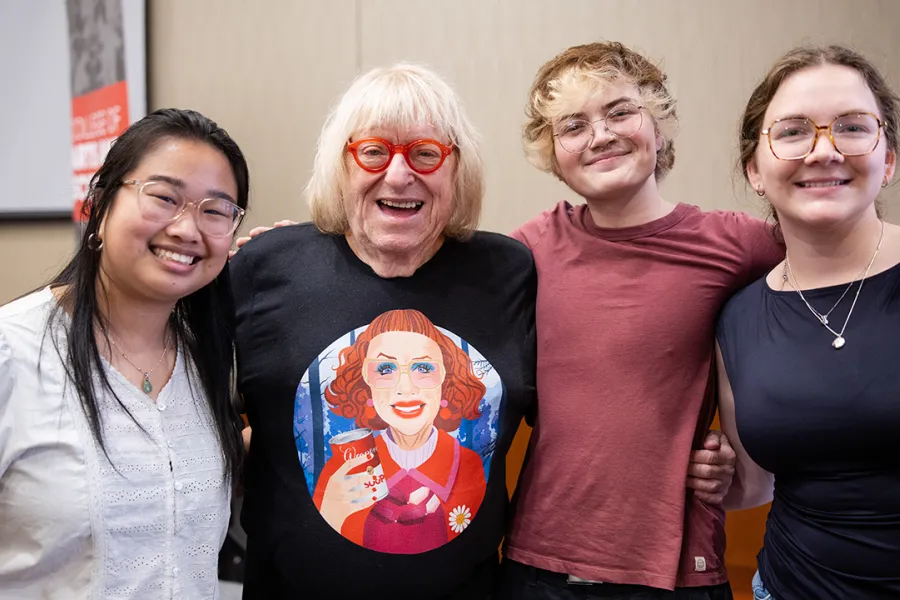 Three journalism students stand with their arms around Bruce Vilanch