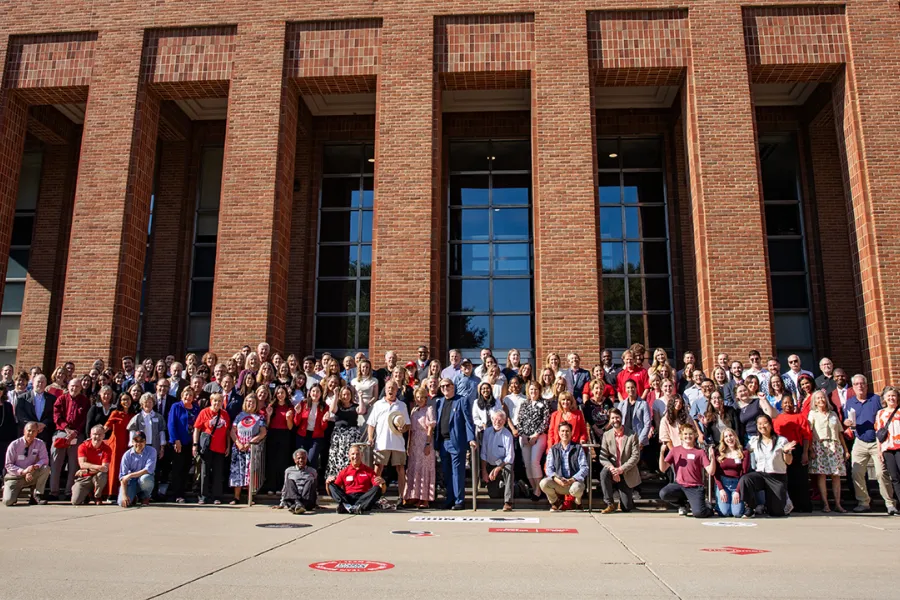 A group of hundreds of Communication Alumni smile in front of the Blackwell Hotel