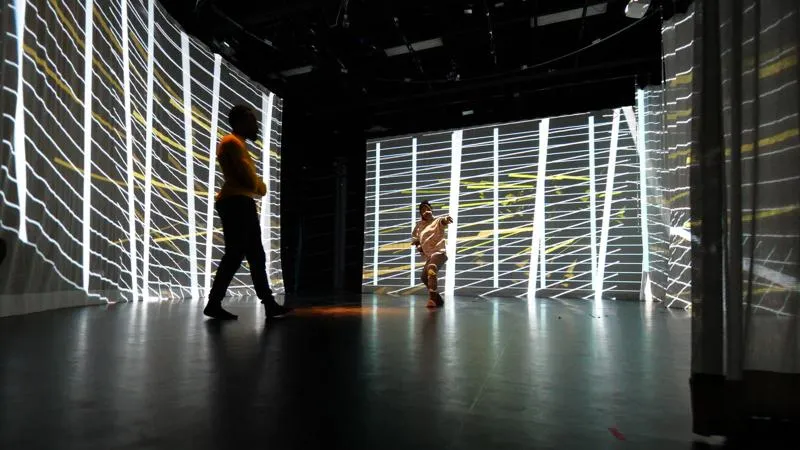 a wall of light strings with silhuettes of people moving through the space