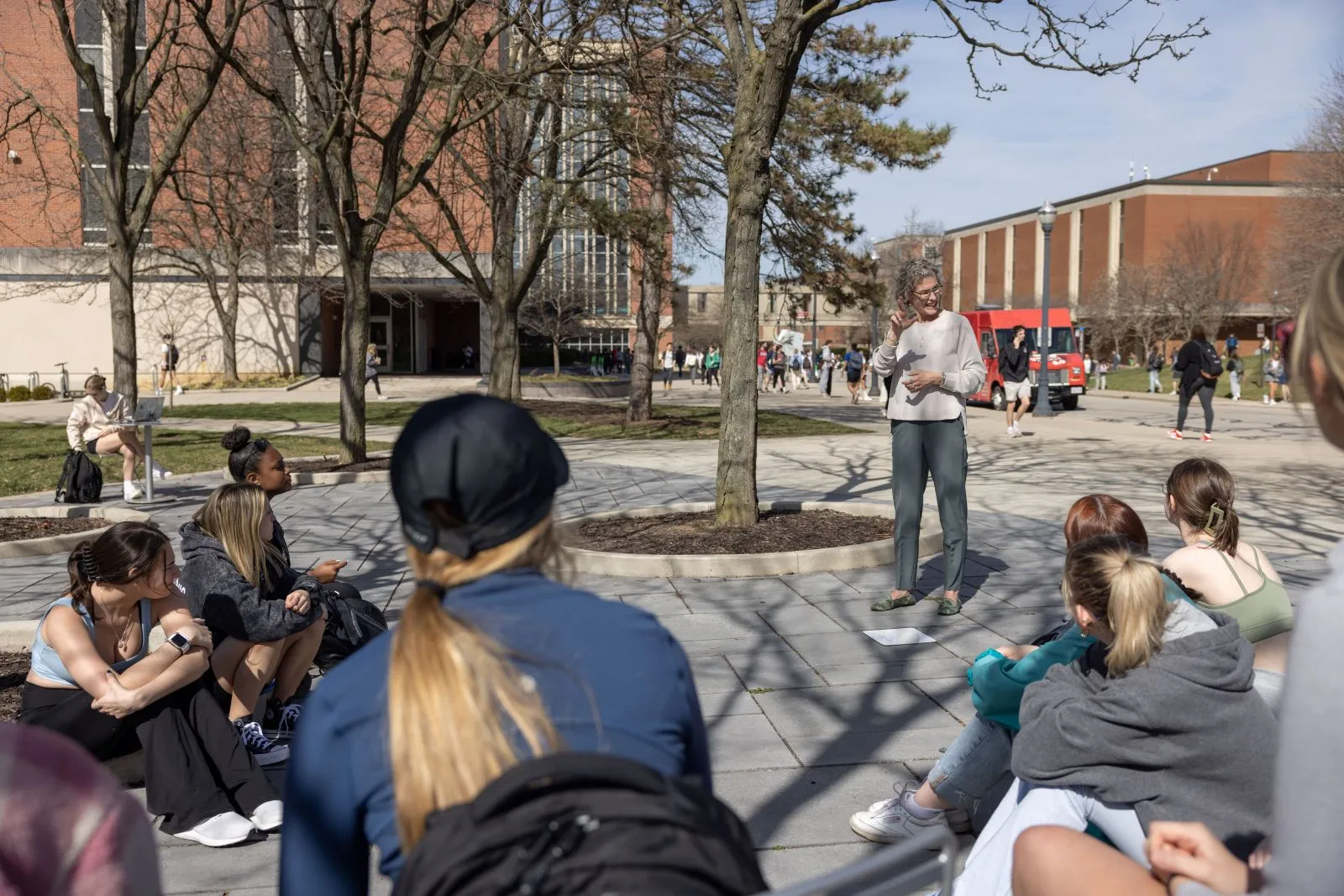 A professor teaching sign language outside on an early Spring day.
