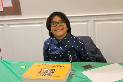 A child poses with his published book about heritage
