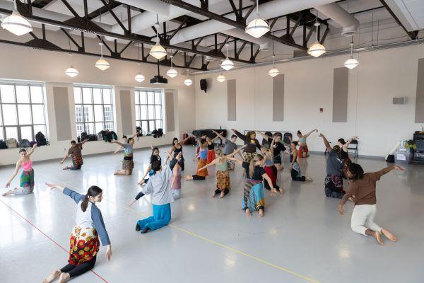 a large dance class in a studio with large windows and plenty of light