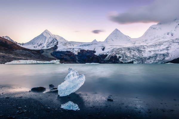 a lake in front of snowy mountains and glaciers