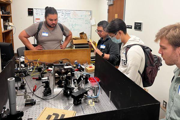 students and faculty look at a physics experiment
