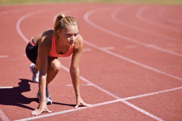 a young female runner at the starting line of a race, looking determined