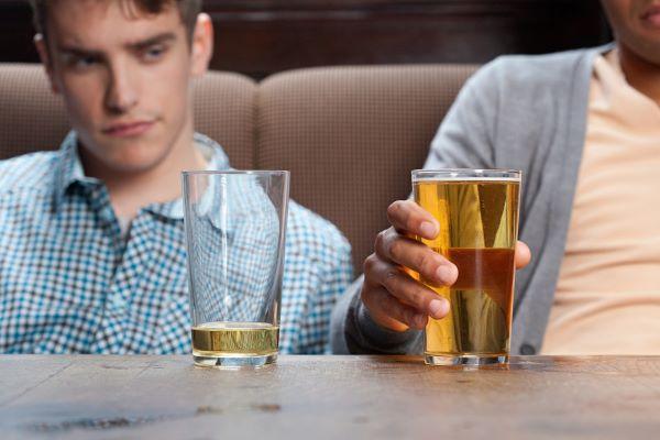 a man looks at his mostly empty beer glass