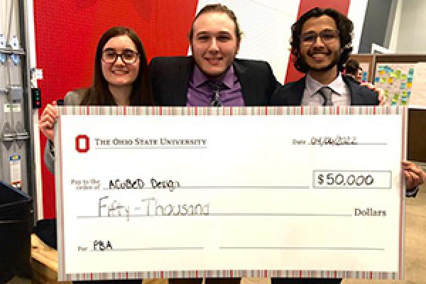 The A Cubed Design team members holding a large check