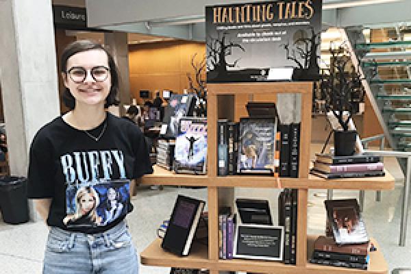 English major Rachel Stewart stands next to the display of horror literature in Thompson Library.