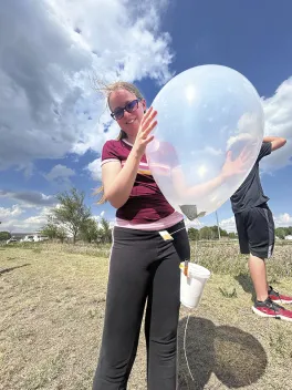 Senior Rachel Lanham preparing to deploy a small weather balloon to investigate the characteristics of temperature, moisture and winds as the balloon ascends.